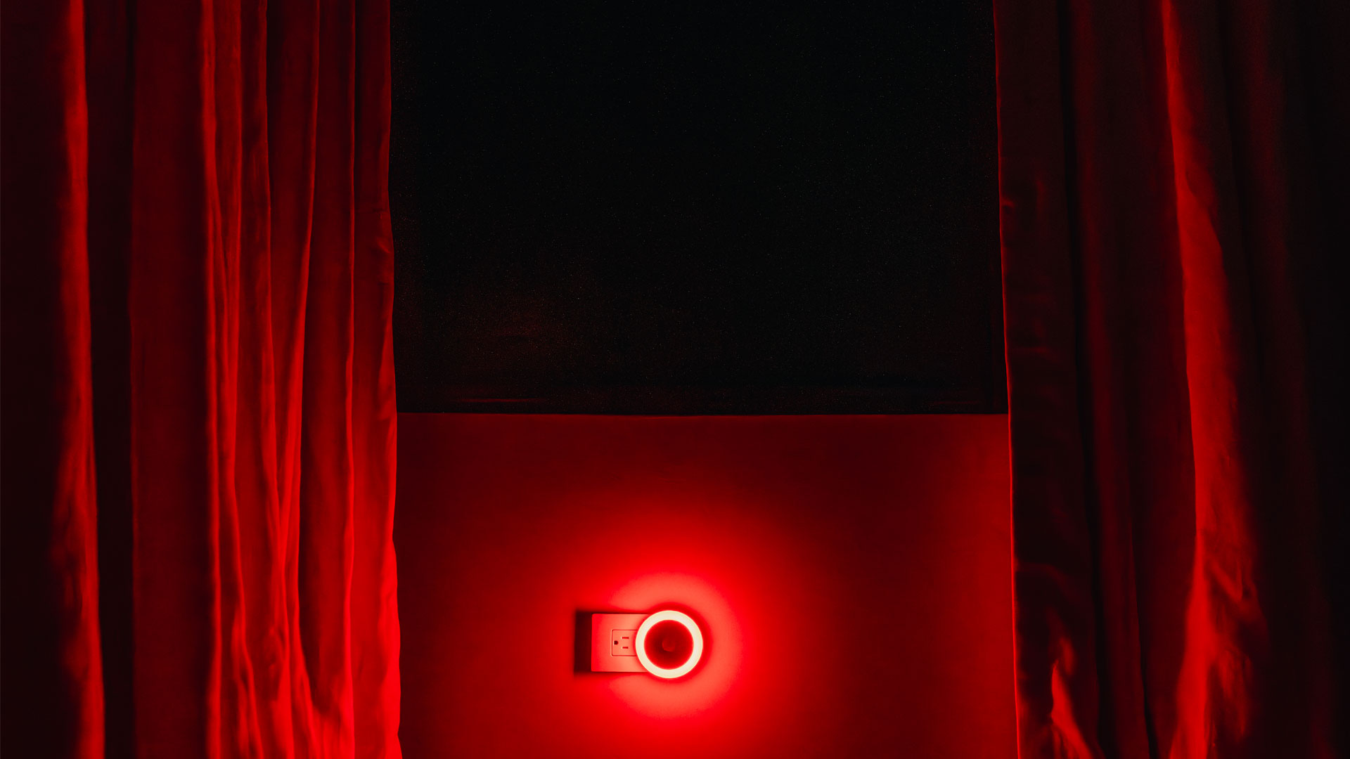 Red curtains with light leaking through window